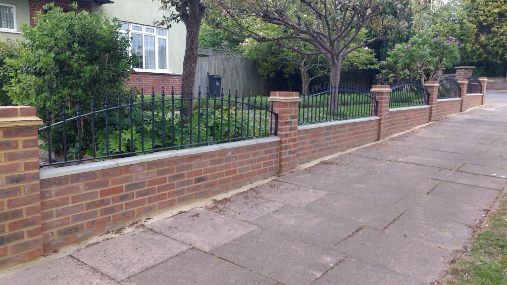 Wrought iron wall railings, with arch top design on garden wall.